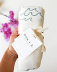 47-inch square Coastal Wave Swaddle Blanket in organic bamboo and cotton with hand-carved block print wave motif, gift-ready