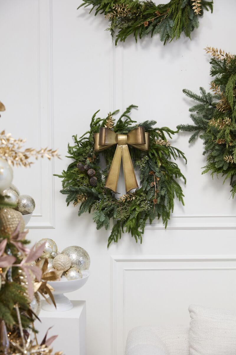 Decorative wreaths with gold bows on a white wall