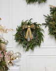 Decorative wreaths with gold bows on a white wall