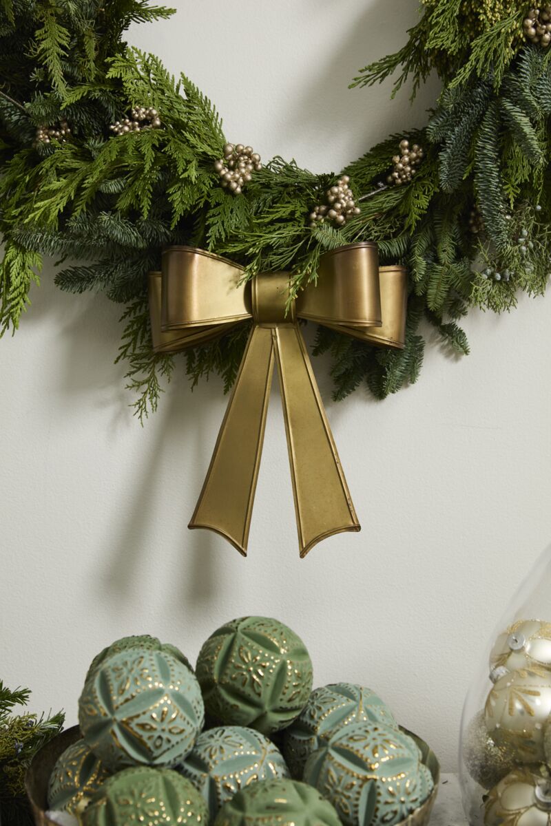 Green wreath with gold bow and decorative balls on a white background