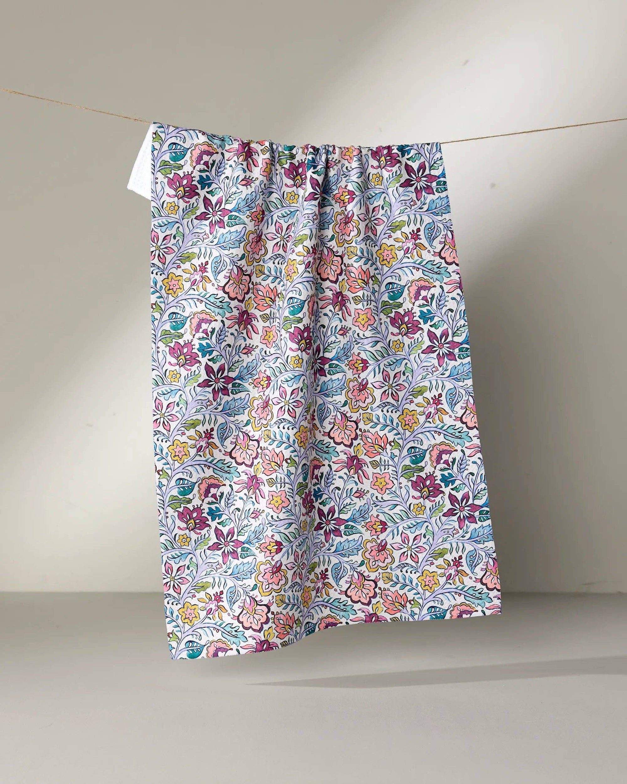 Floral patterned skirt hanging on a line against a plain background