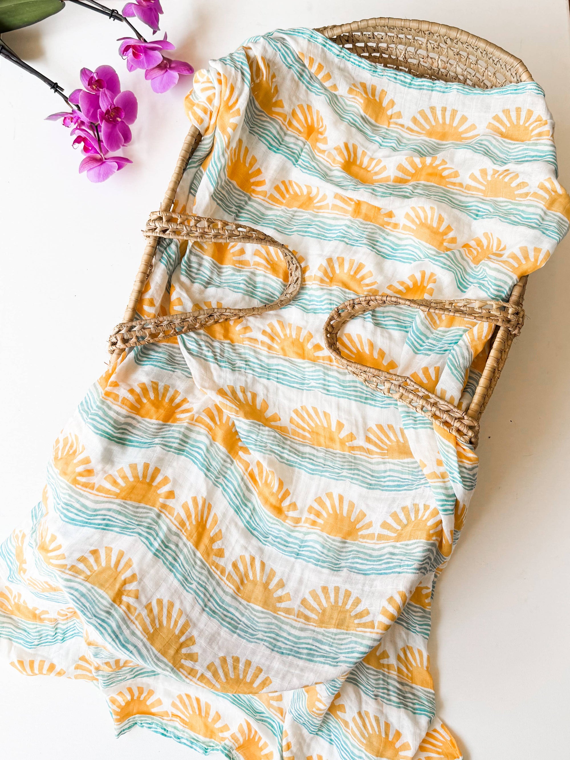 Eco-friendly baby swaddle with sun and wave print, inspired by Maui’s coastal style