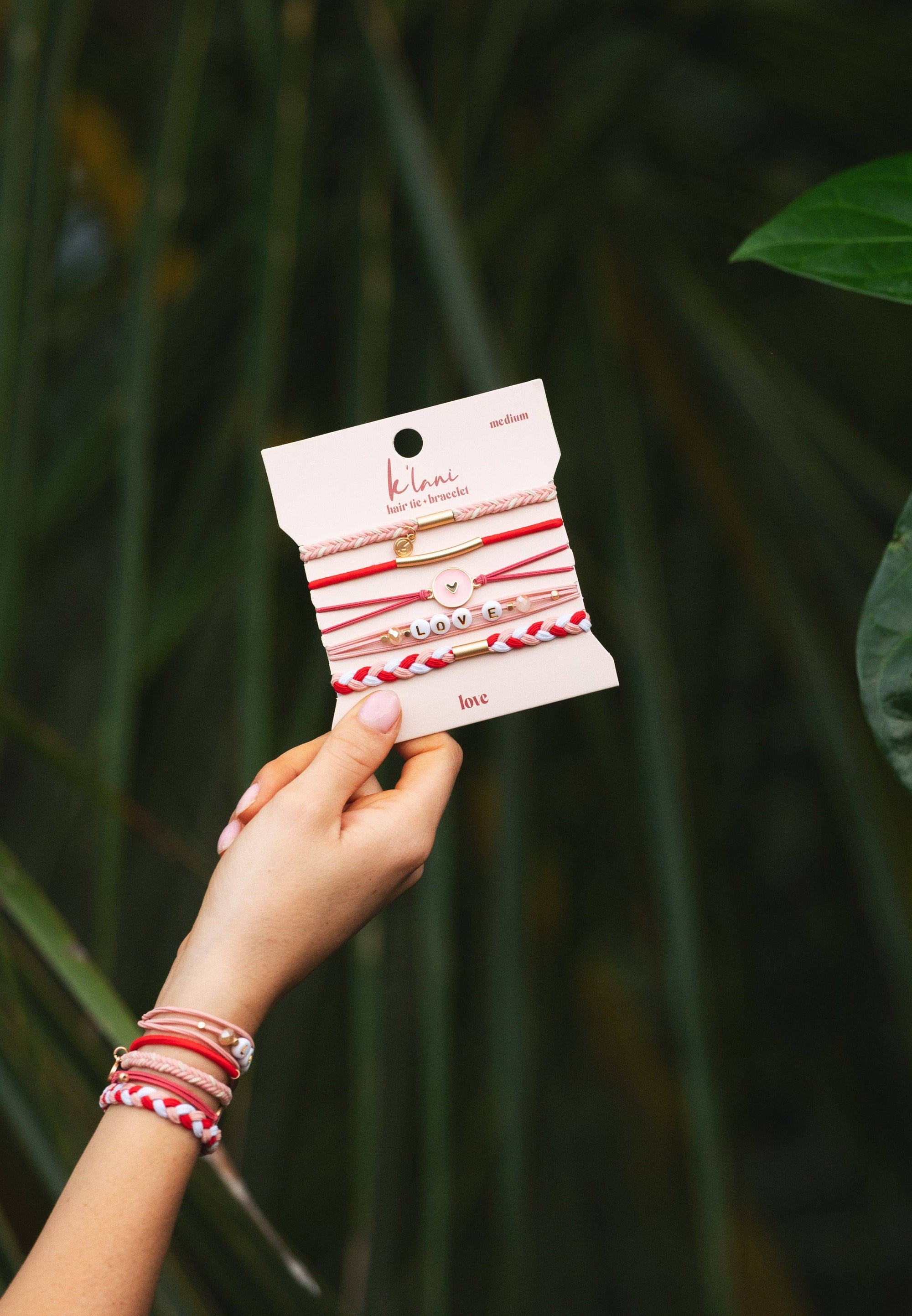 Pink and red hair tie bracelets with heart charm displayed in three sizes